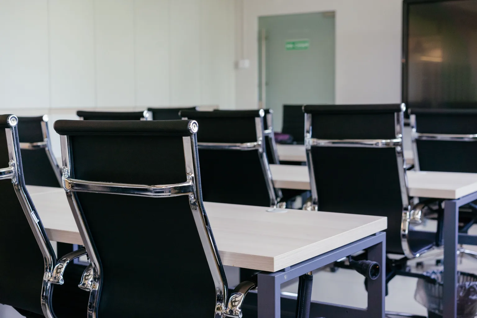 An empty modern conference room with chairs pushed under a long table