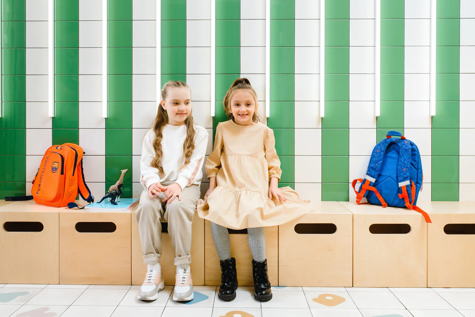 Two young students sitting with backpacks at the start of a school day