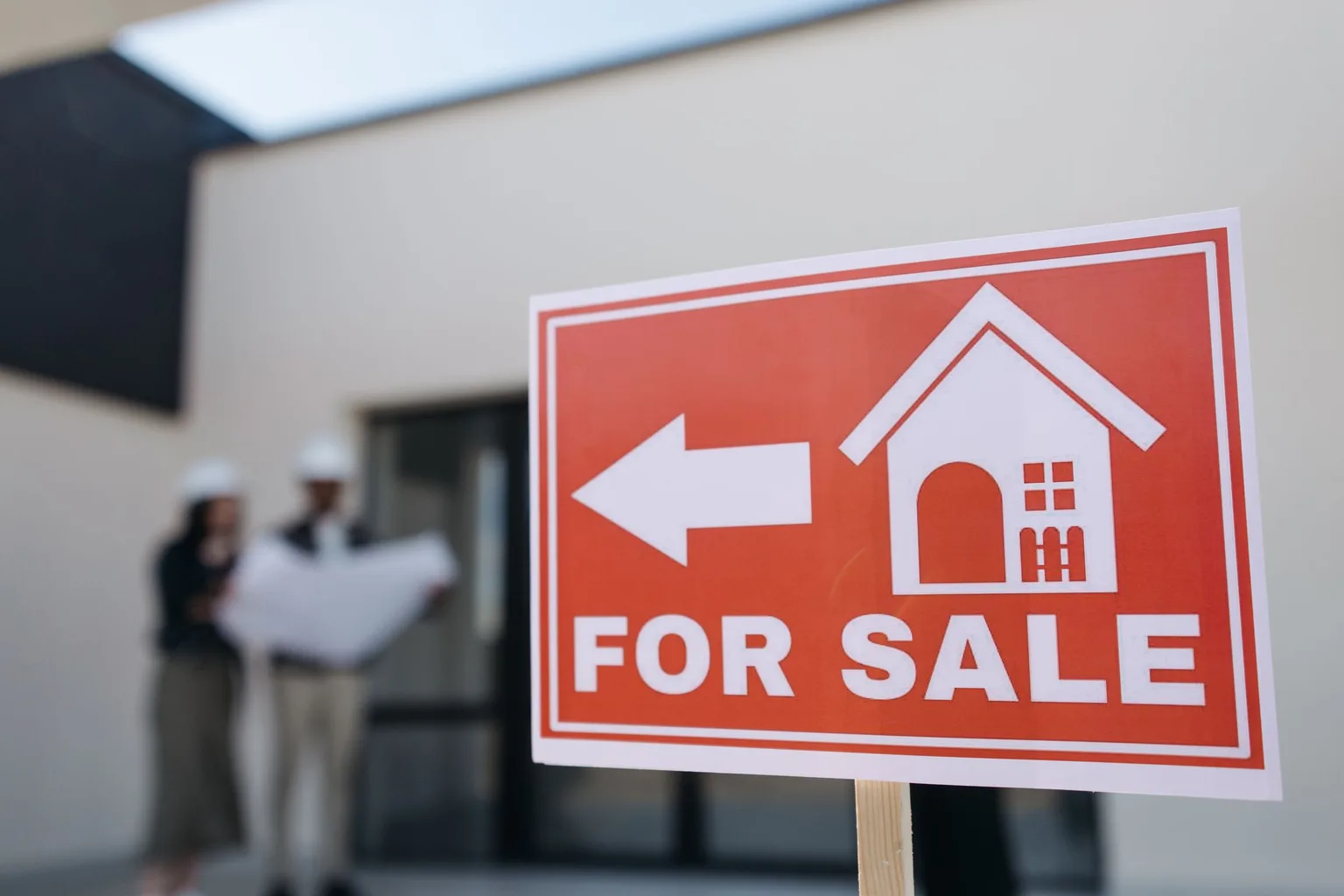 A red house for sale sign posted outside a home