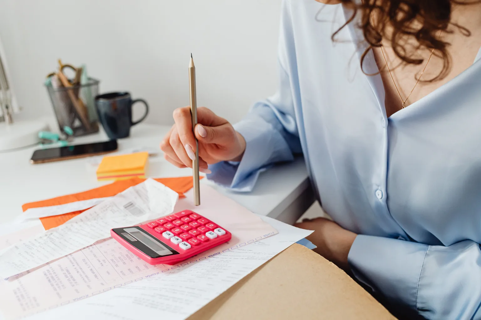 A person working through paperwork and receipts with a calculator at a desk