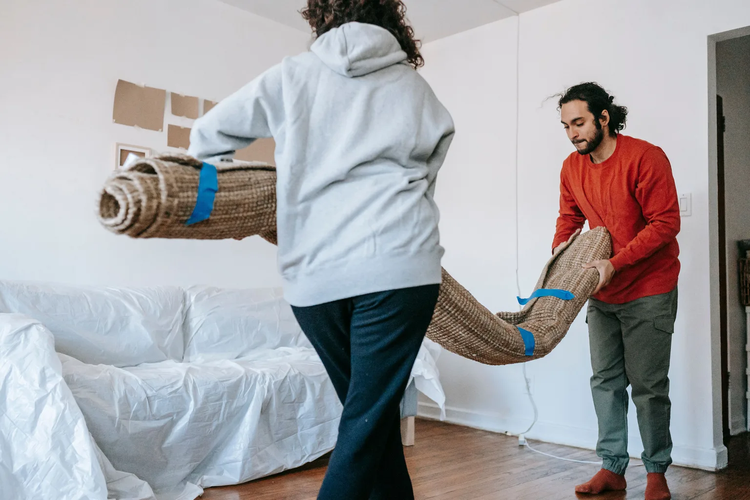 A couple unrolling new carpet in an empty room