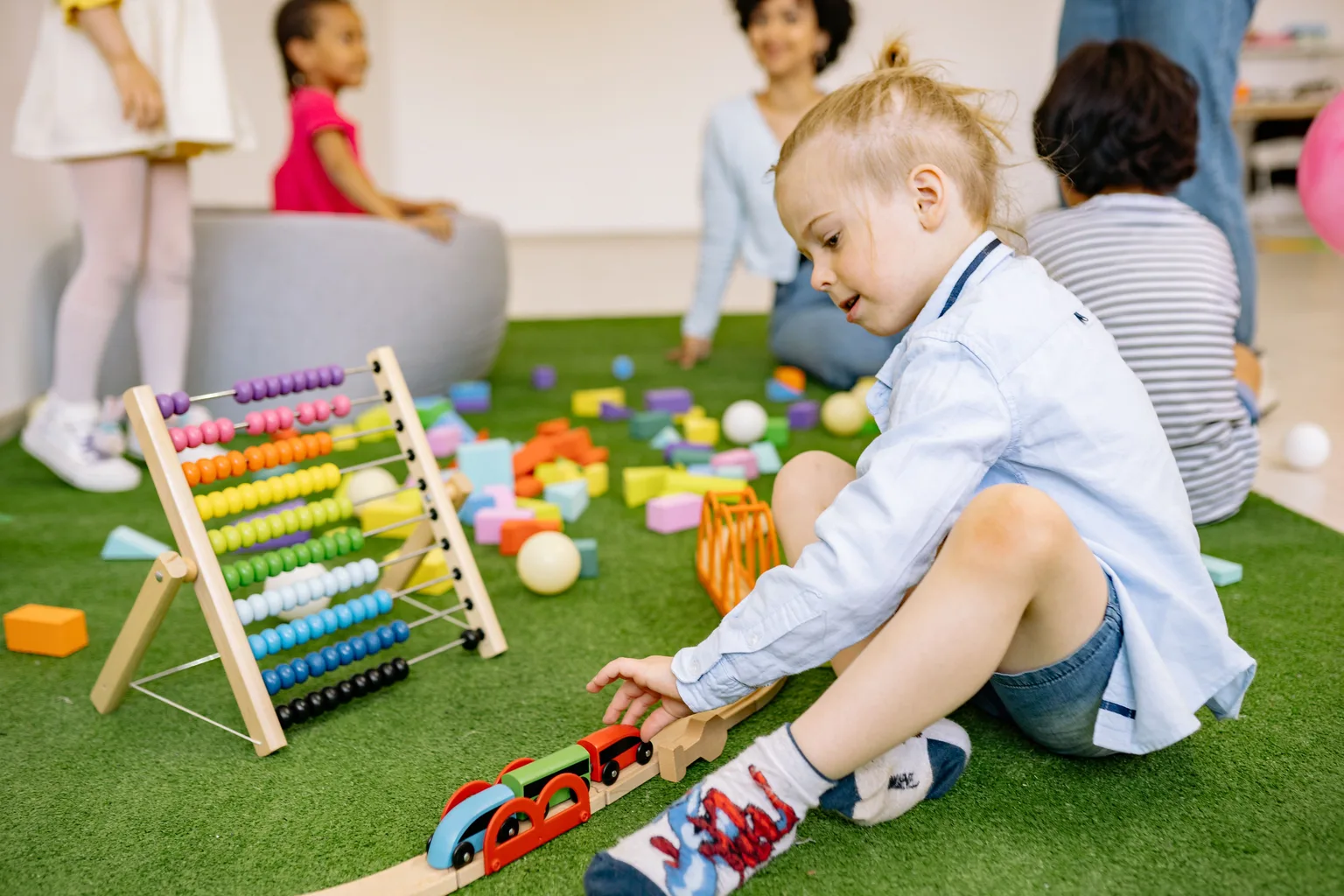 Children playing with toys on the floor of a bright classroom