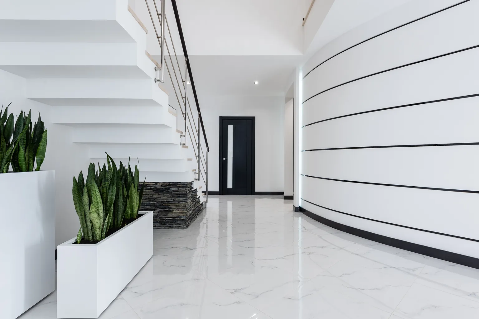 A bright community building hallway with a polished floor and stairway