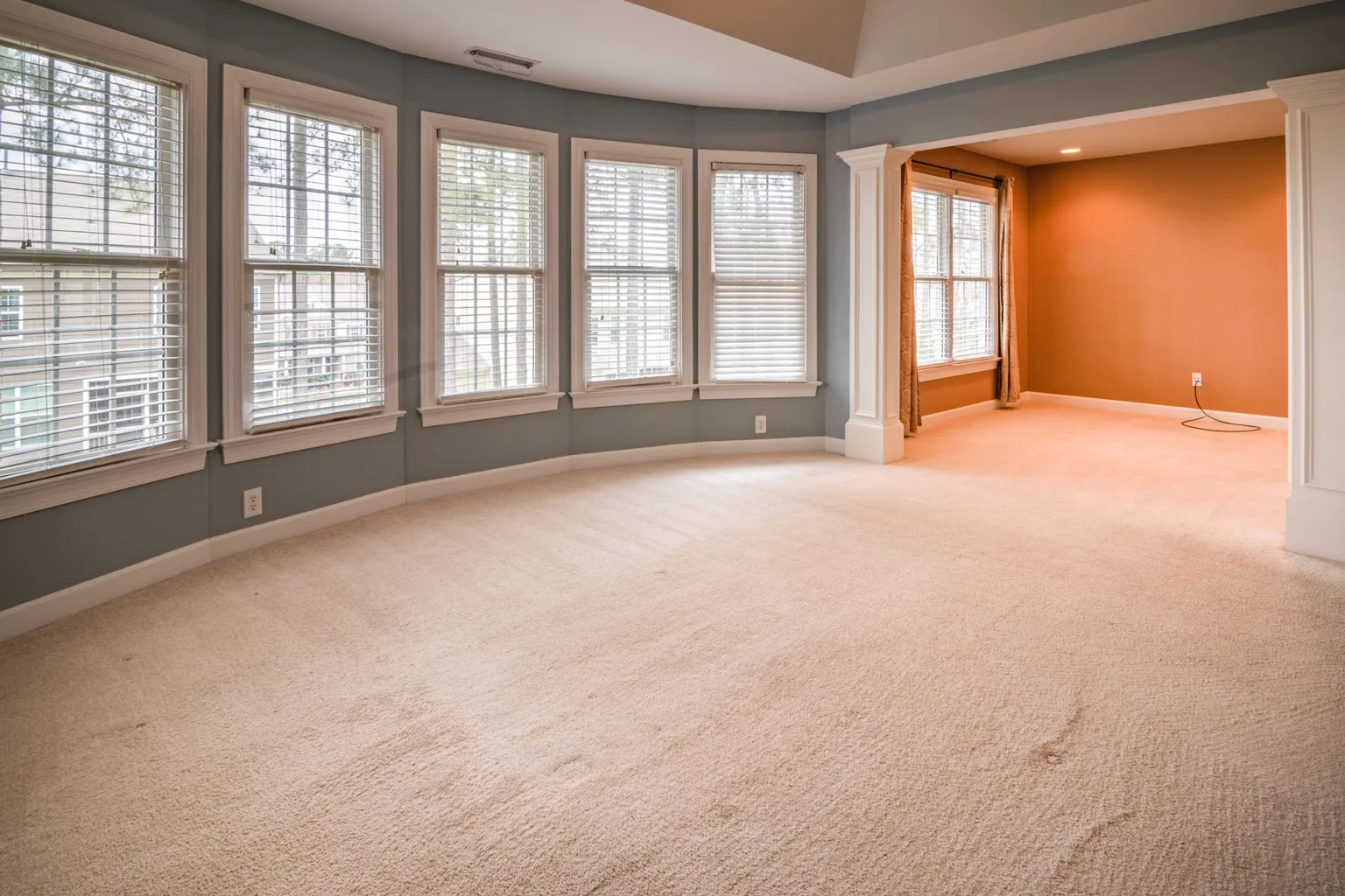 A living room with plenty of windows and carpeted flooring