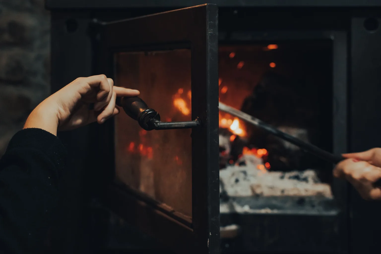 A person pushing firewood into a furnace