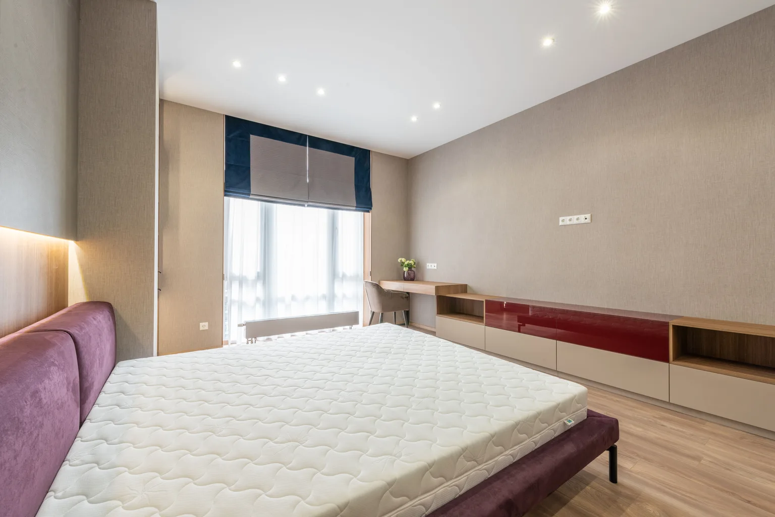 A bare mattress on a bed in a bright, simply furnished bedroom