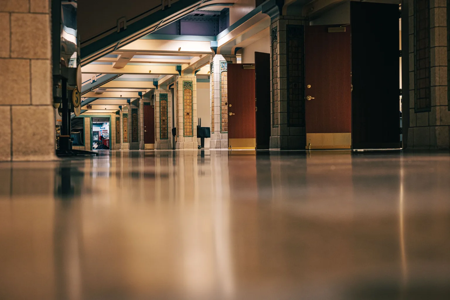 An empty corridor with a polished floor reflecting overhead lighting