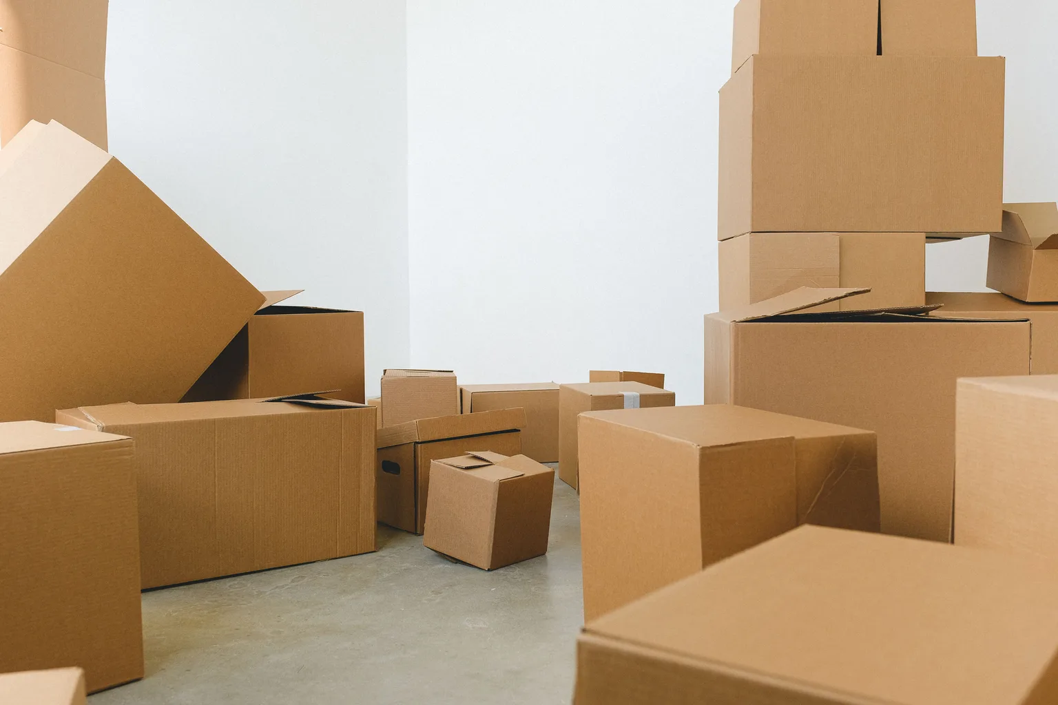 Cardboard moving boxes stacked and scattered across the floor of an empty room