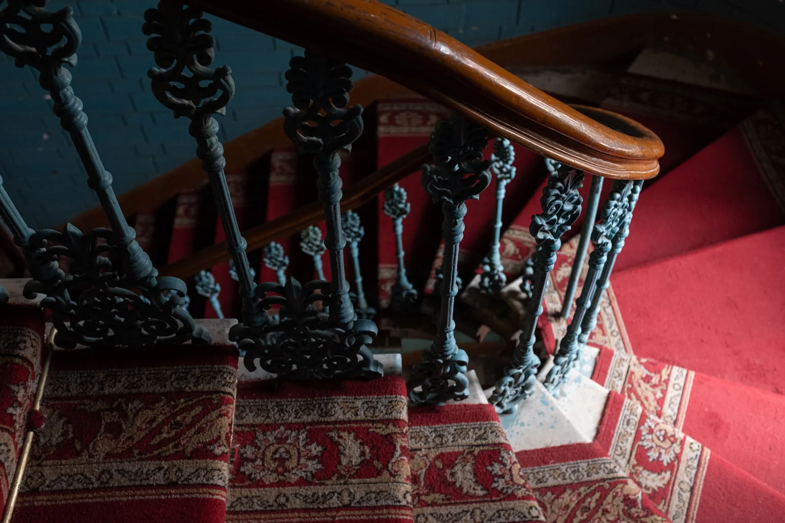 A carpeted staircase with a patterned runner and iron railing