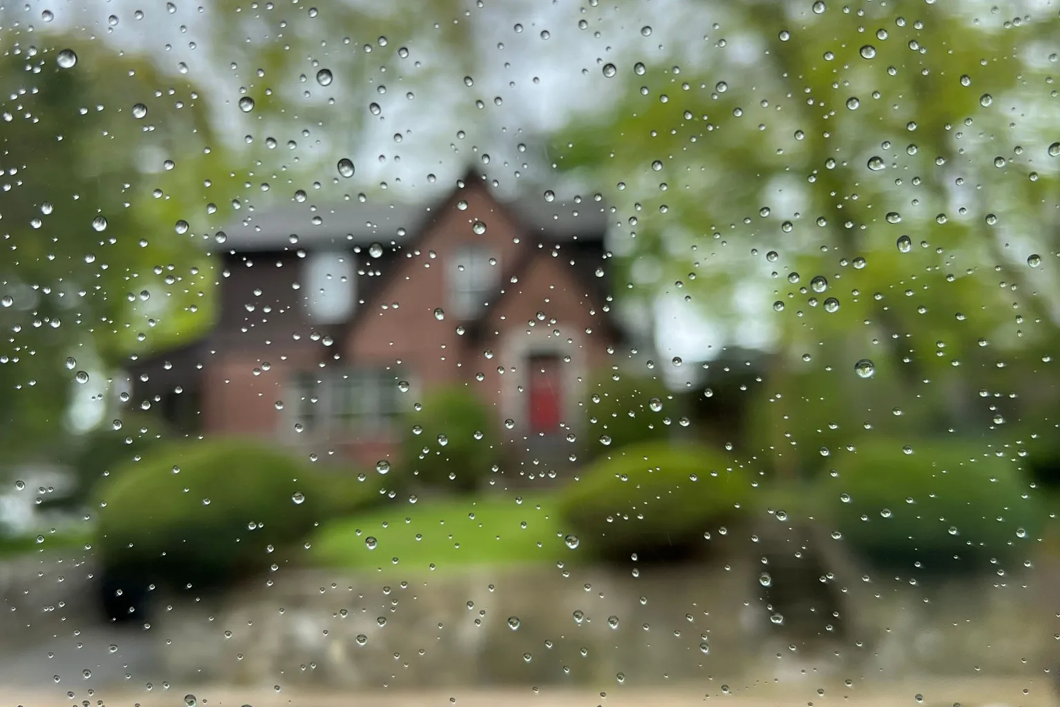 A cottage seen through raindrops on a window pane