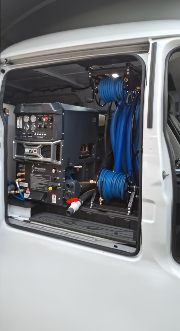 All City truck-mount carpet cleaning equipment with blue solution hoses inside a service van